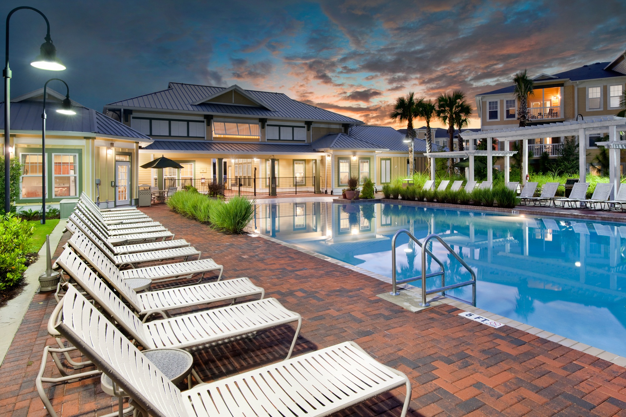 A poolside area with sun loungers and a building in the background.